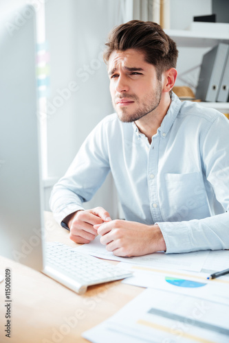 Concentrated young businessman working with computer in office