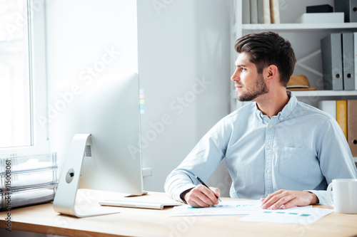 Pensive businessman sitting with laptop at office