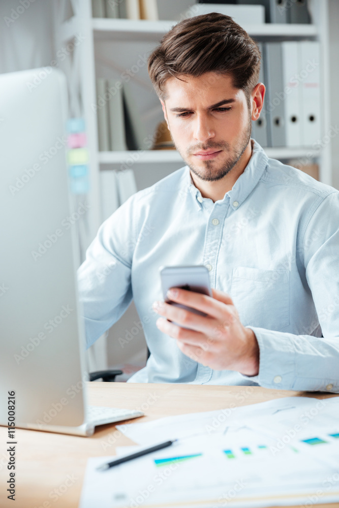 Businessman sitting at the table and using smartphone in office Businessman sitting at the table and using smartphone in office