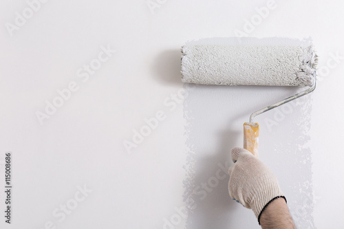 Close up of painter hand painting a wall grey with paint roller photo