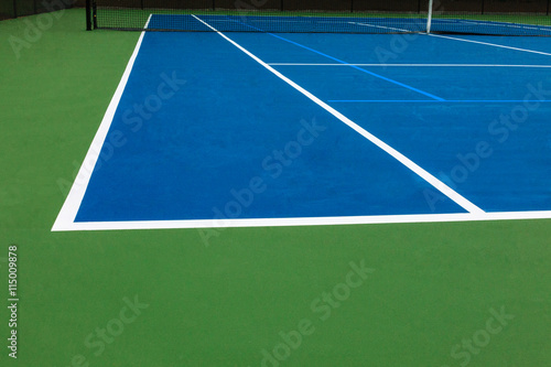 Blue tennis court surface with green texture, white lines and black net