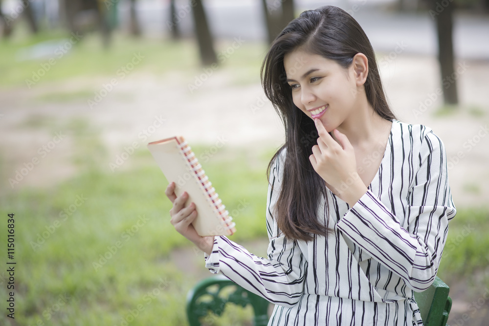 Fototapeta premium Attractive woman reading a book in the park