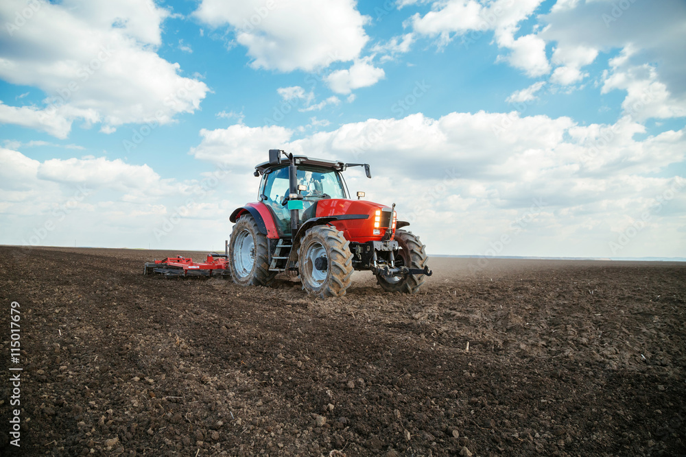 Farmer in tractor preparing land with seedbed cultivator Farmer in tractor preparing land with seedbed cultivator