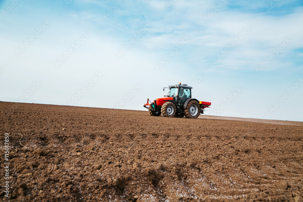 Fototapeta premium Farmer fertilizing arable land with nitrogen, phosphorus, potassium fertilizer