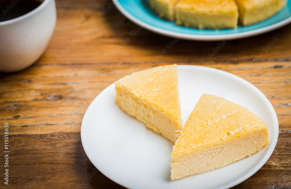 Slice of Plain Cheesecake on white plate on wooden background