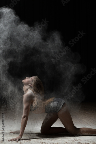 Female dancer sprinkle flour on black background