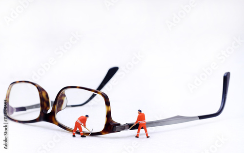 Miniature technician repairing reading glasses. Business concept