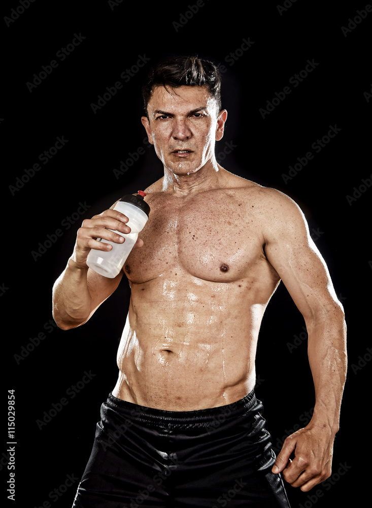 attractive strong sport man drinking water holding bottle sweating tired after training hard on gym attractive strong sport man drinking water holding bottle sweating tired after training hard on gym