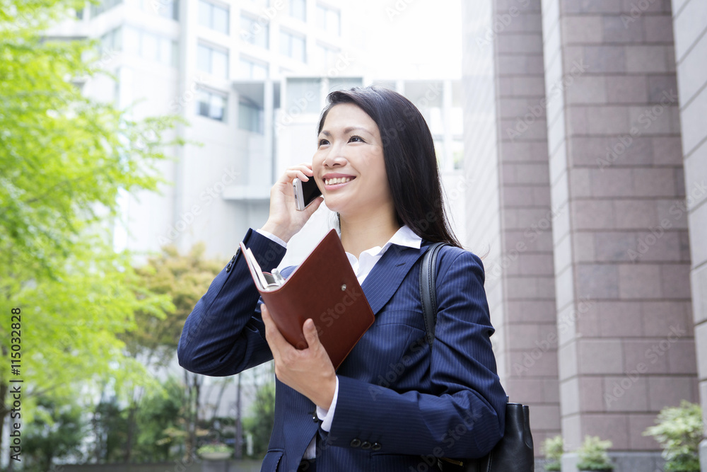 Fototapeta premium 電話をする若い女性 屋外ビジネスイメージ