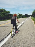 Red head woman riding bike along highway
