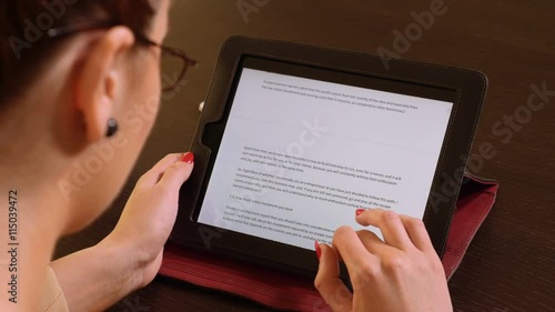 Young beautiful business woman sitting at a table and reading on tablet pc