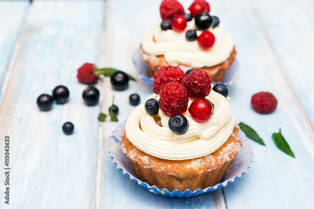 cupcakes decorated with cream cheese frosting and fresh berries on a wooden background cupcakes decorated with cream cheese frosting and fresh berries on a wooden background