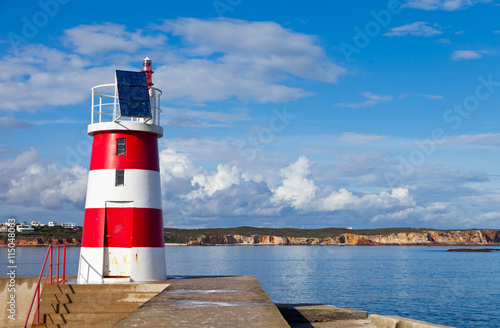 Harbor lighthouse with solar panel against a blue sky