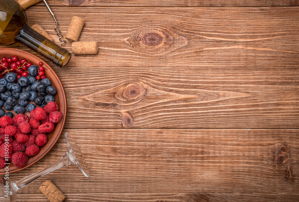 Bottle of wine with berries and corks on wooden table. Background.