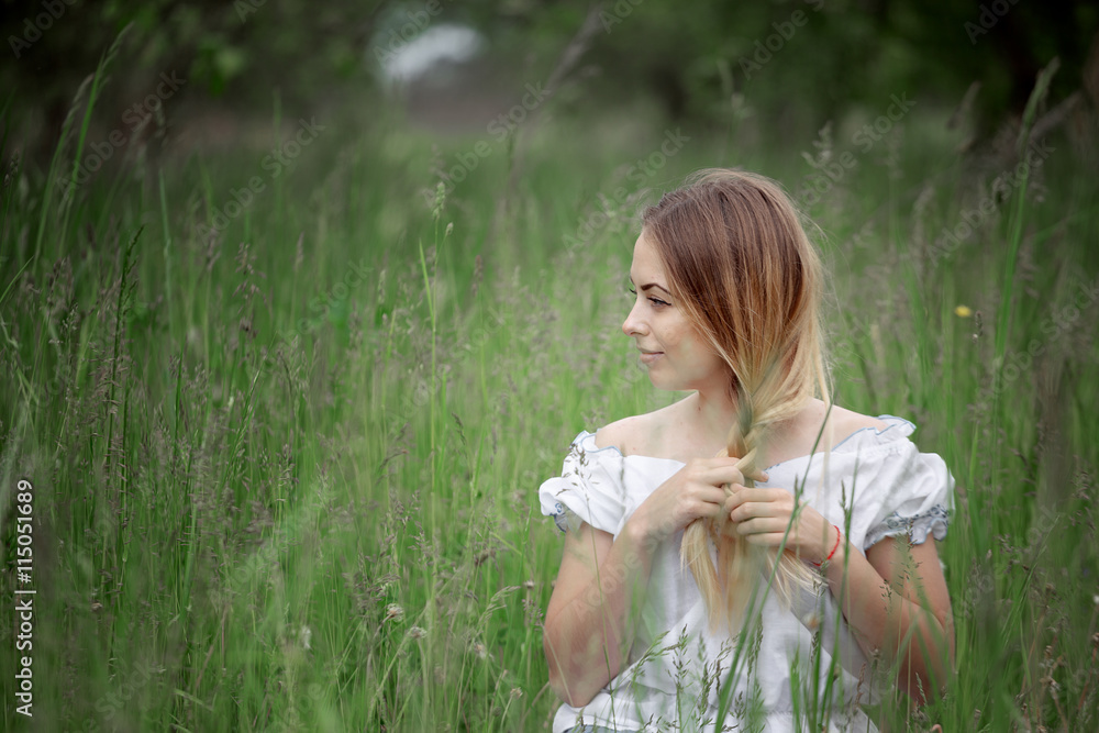 Blonde girl in shorts sitting on the grass outdoors Blonde girl in shorts sitting on the grass outdoors