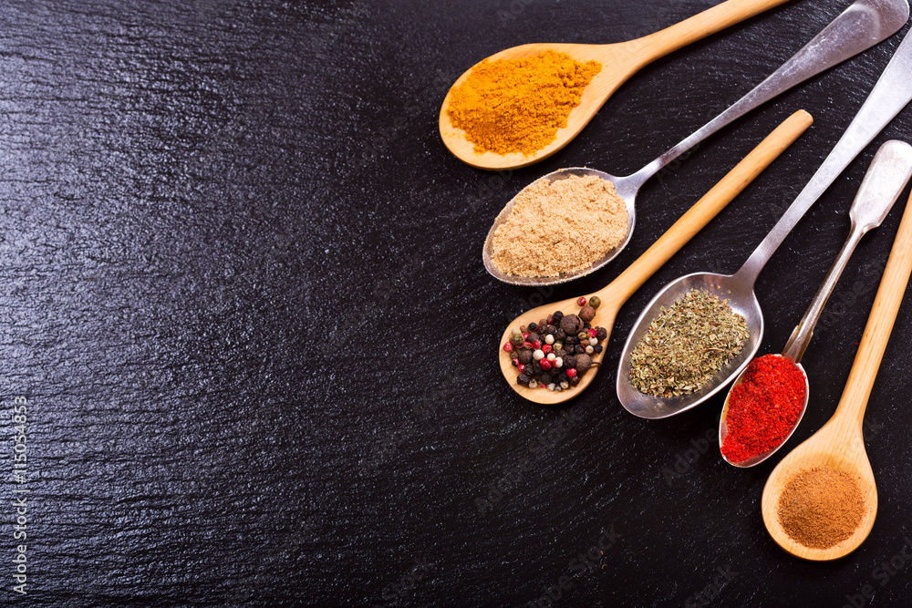 Fototapeta premium various spices in spoons on dark background
