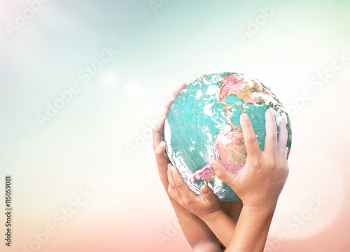 Earth Day concept: Earth globe in family hands over blurred nature background. Elements of this image furnished by NASA