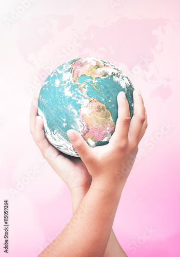 World environment day concept: Earth globe in two human hands over blurred pink nature background. Elements of this image furnished by NASA