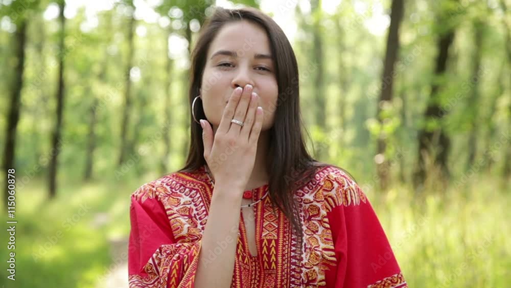Beautiful girl in red dress smiling against green background, blowing a kiss Beautiful girl in red dress smiling against green background, blowing a kiss