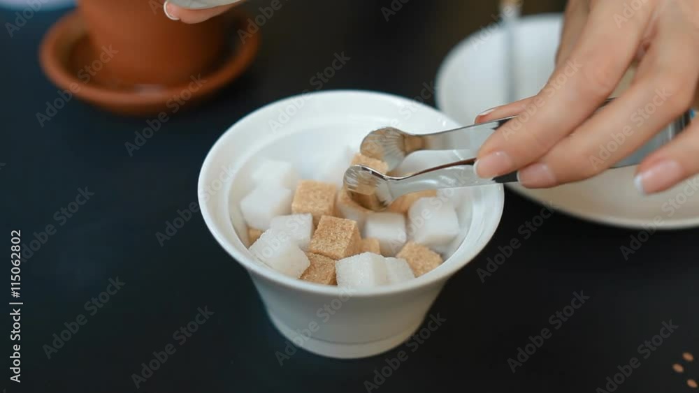 Woman takes sugar from the sugar tongs Woman takes sugar from the sugar tongs