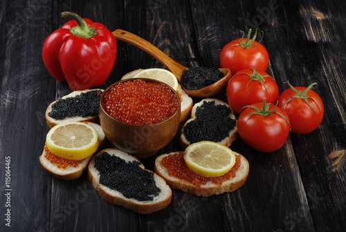 red and black caviar with bread and vegetables on wooden background 
