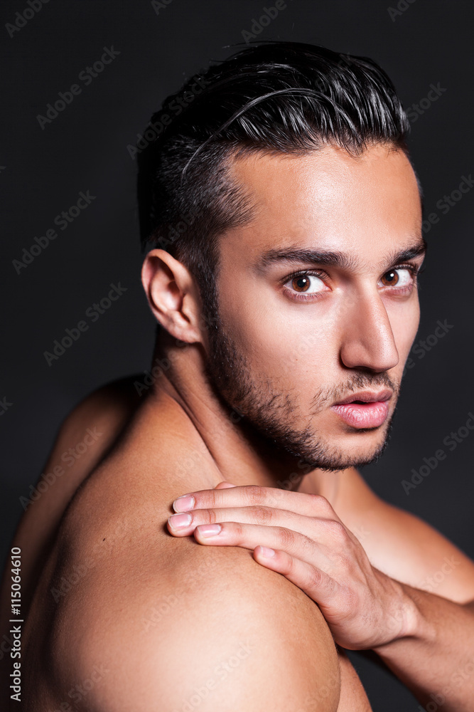 Sexy and expressive shirtless male model flirting against black background
