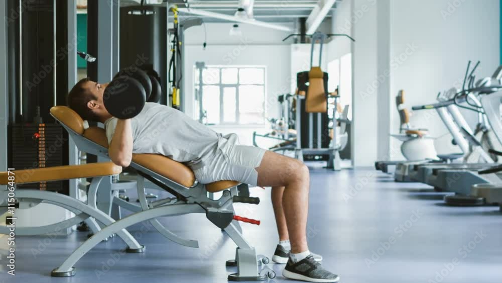 Man In Gym Exercising Chest On The Bench with dumbbells. Sport concept. Man In Gym Exercising Chest On The Bench with dumbbells. Sport concept.