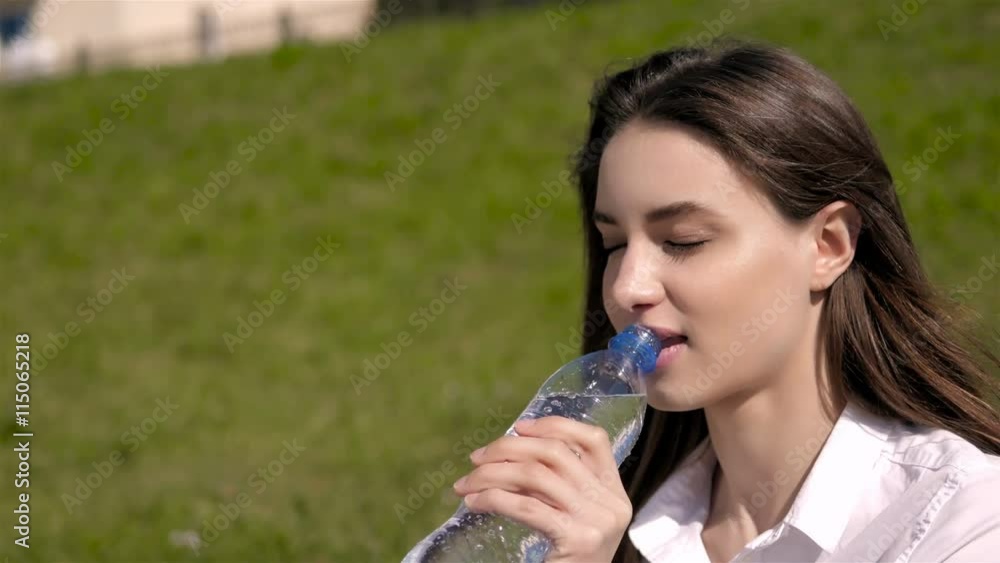 Beautiful Brunette With Long Hair In The Wind Drinking From a Bottle of Water Beautiful Brunette With Long Hair In The Wind Drinking From a Bottle of Water
