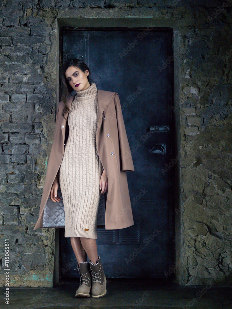 Elegant fashion model wearing long mocha coat, posing before a door. Elegant fashion model wearing long mocha coat, posing before a door.
