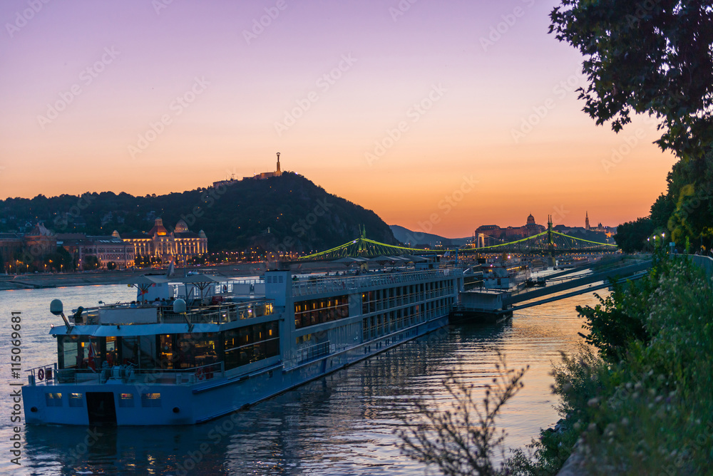 big touristic steamboat on Danube at sunset with cityscape of Budapest on the background