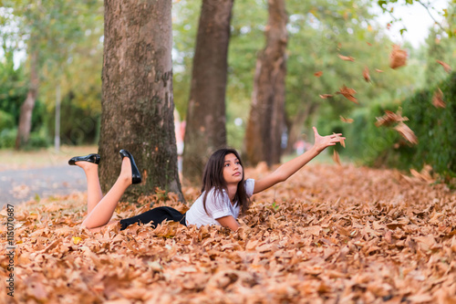 Young girl playing with autumn leaves