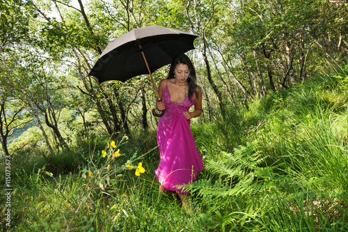 Woman walking in the woods with black umbrella. romantic situation 