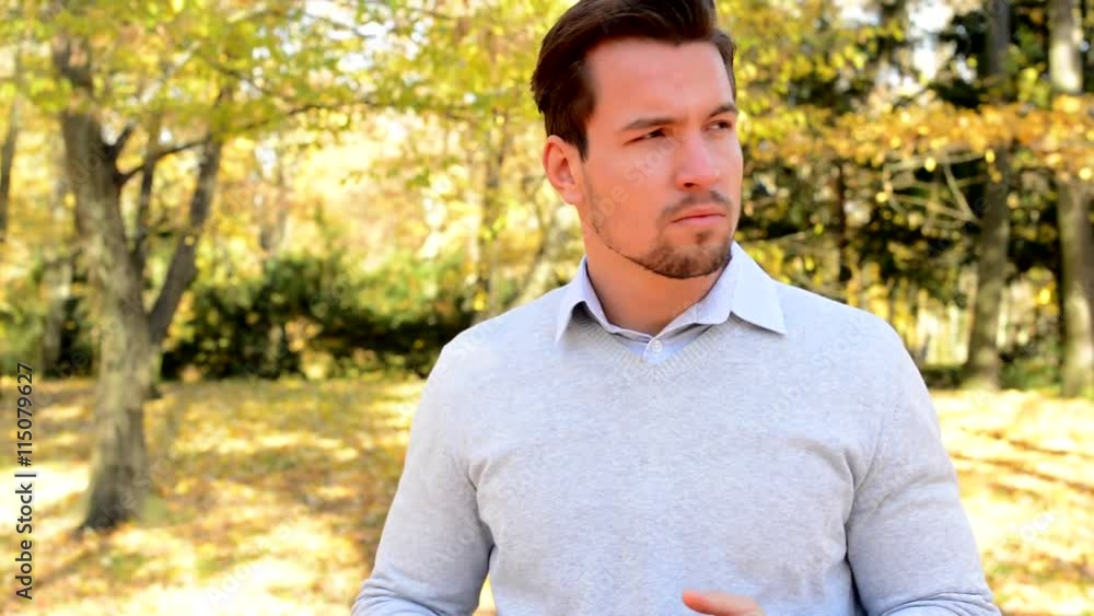 Young man stands in the woods, holds head in plams, is confused and looks around Young man stands in the woods, holds head in plams, is confused and looks around