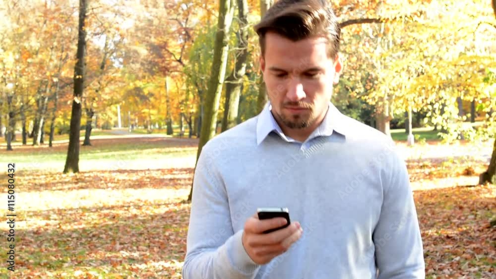 Young handsome man goes through the woods and works on phone Young handsome man goes through the woods and works on phone