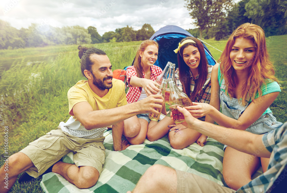 happy friends with tent and drinks at campsite happy friends with tent and drinks at campsite