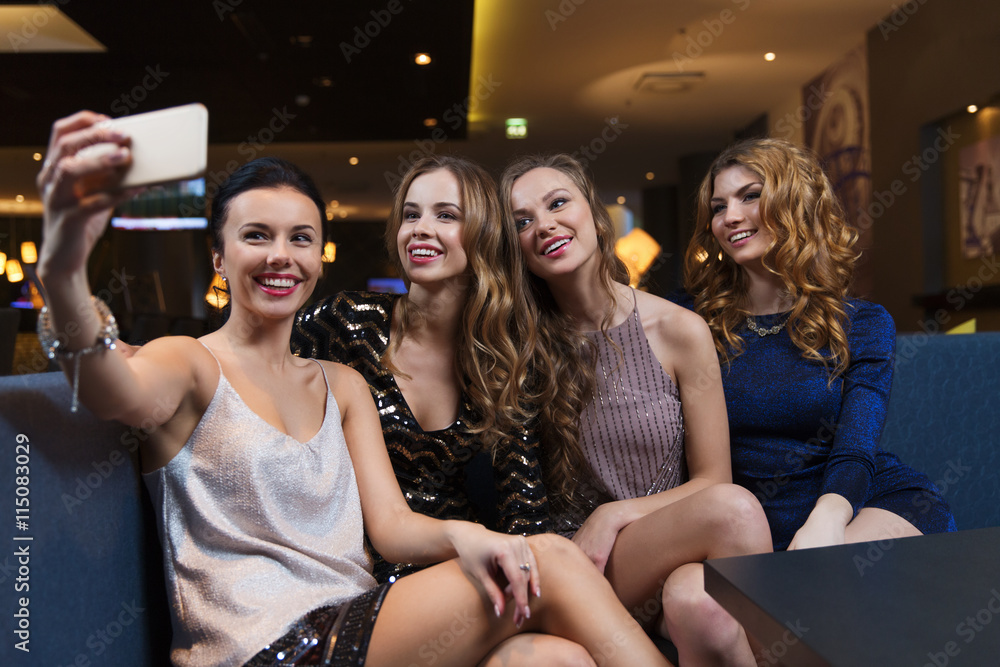 women with smartphone taking selfie at night club