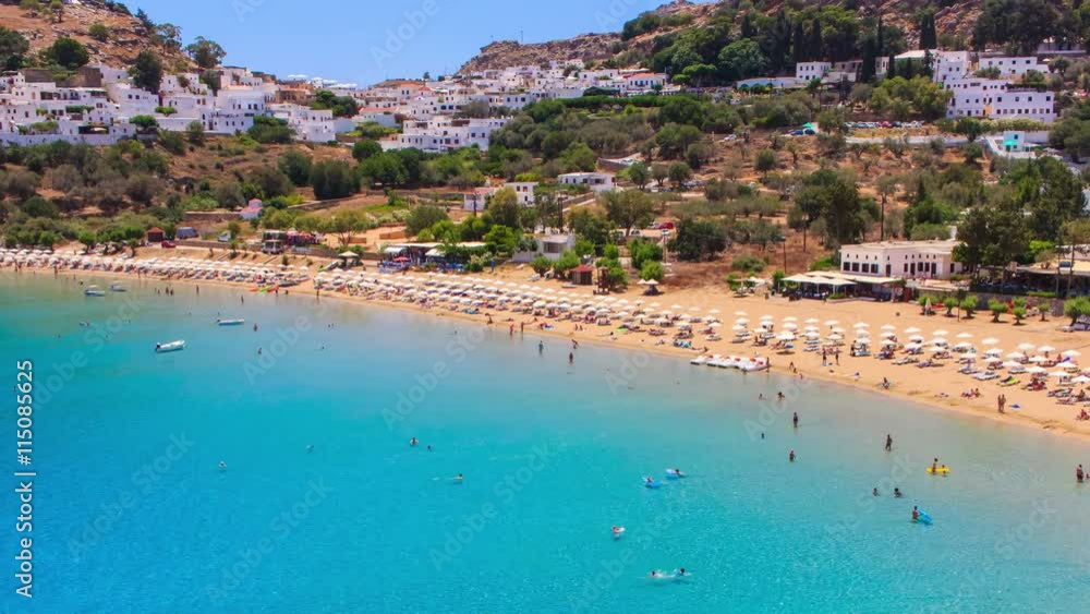 timelapse tourists relax on sunny day at beach. Many people on holiday in Lindos , Greece. Mediterranean sea. timelapse tourists relax on sunny day at beach. Many people on holiday in Lindos , Greece. Mediterranean sea.