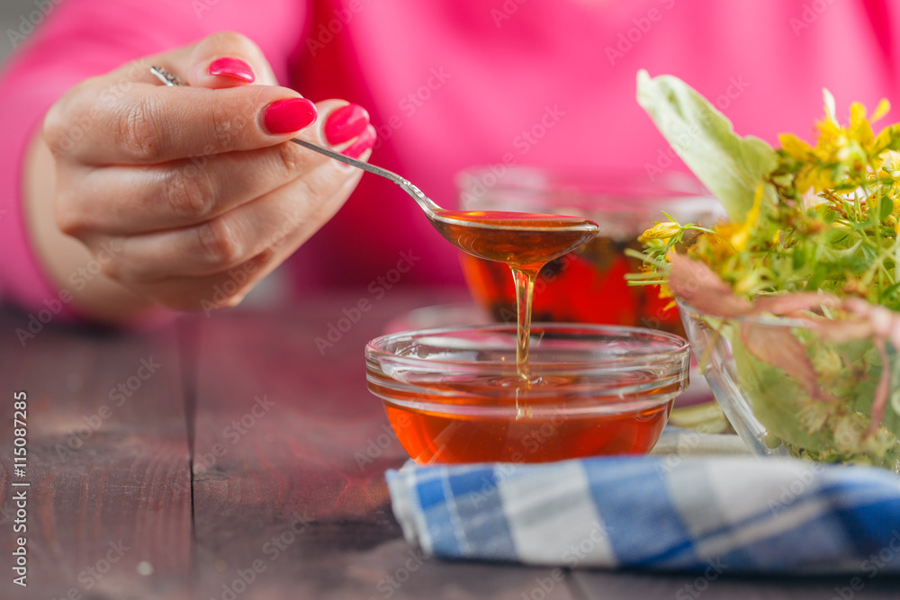 Woman honey scooping with lime-blossom on table Woman honey scooping with lime-blossom on table