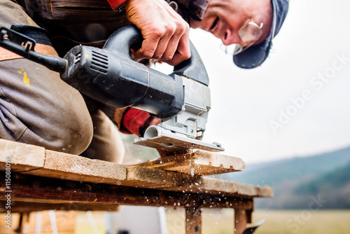 Foto Man grinding planks of wood for home construction.