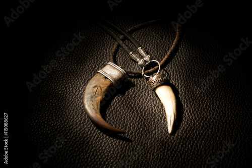Obraz na plátně Carved tusk pendant of bone on the leather background