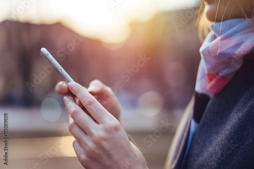 Girl walks in the park and check the messages on your mobile phone. Blurred background  flare light.