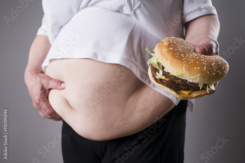 Fat women suffer from obesity with big hamburger in hand, junk food concept