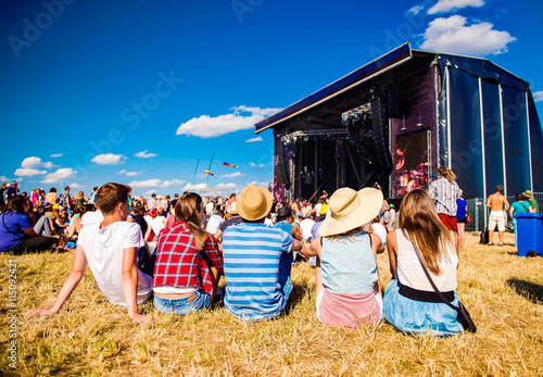 Teenagers, summer music festival, sitting in front of stage photo