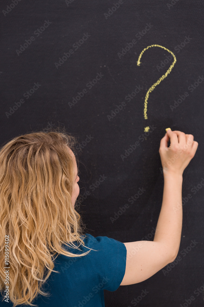 Young girl drawing question mark on a black background. Business woman drawing question mark on the board. Teacher hand drawing question mark on chalkboard. Education and idea concept.