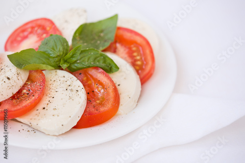 Fresh Italian Caprese Salad with Mozzarella Cheese, Tomatoes and Basil on white plate. Healthy food concept