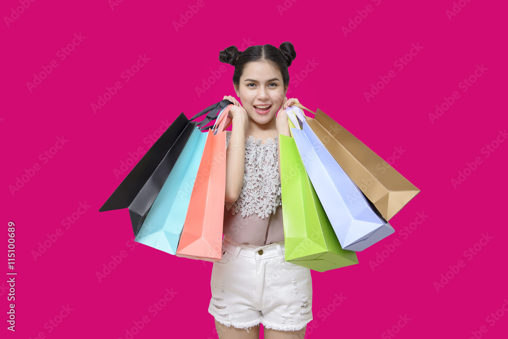 Attractive shopper woman holding shopping bags on pink backgroun