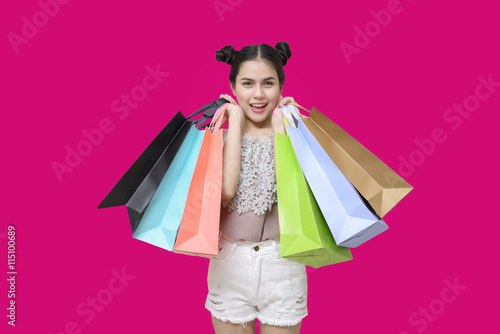 Attractive shopper woman holding shopping bags on pink backgroun