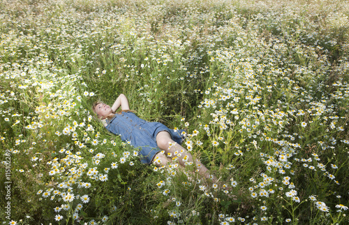 The beautiful happy young woman lies in the field of chamomiles....