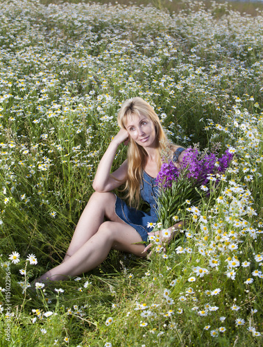 The happy young woman in the field of camomiles..