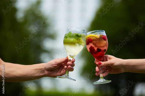 Foto Hand holding glasses cocktail clinking together at outdoor.